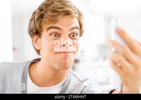 Always young at heart. a young woman making funny faces while taking selfies with his smartphone. Stock Photo