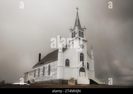 A beautiful old church with peeling paint along the side and a refinished front in a springtime countryside landscape Stock Photo