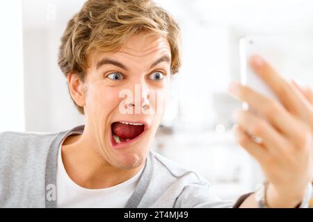 Life is long be silly. a young woman making funny faces while taking selfies with his smartphone. Stock Photo