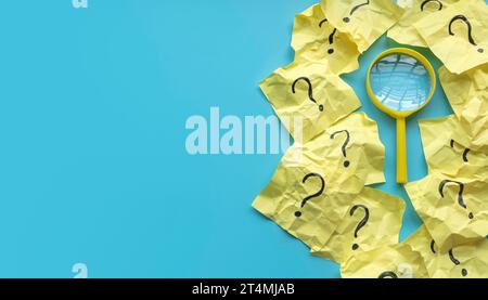 QnA or questions and answers concept. Yellow magnifying glass with question symbol on memo note over a blue background. Copy space for text. Stock Photo