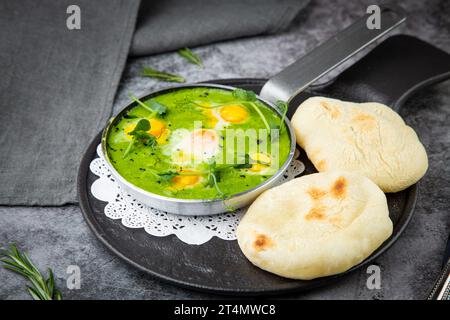 creamy broccoli soup in a frying pan with tortillas against a dark background, side view Stock Photo