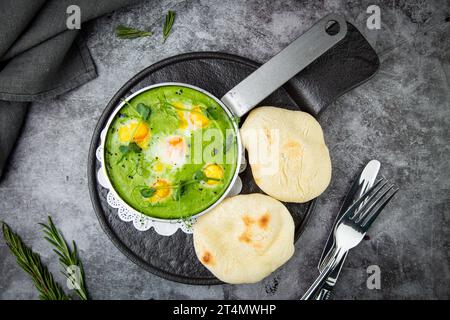 creamy broccoli soup in a frying pan with tortillas against a dark background, top view Stock Photo