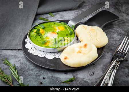 creamy broccoli soup in a frying pan with tortillas against a dark background, side view Stock Photo