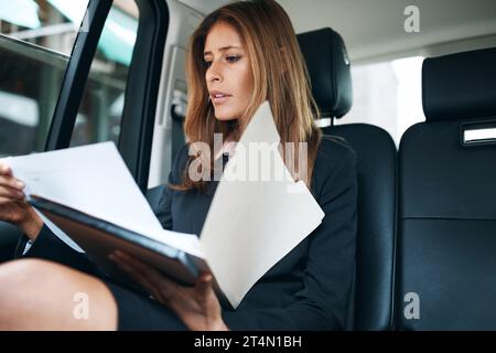 Success waits on no one. a mature businesswoman going through paperwork in the back seat of a car. Stock Photo