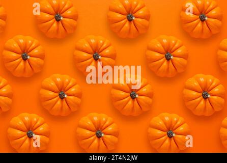 Flat lay repetitive design of Autumn Pumpkins on orange background Stock Photo