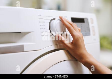 Hand of person choosing right washing cycle on machine Stock Photo