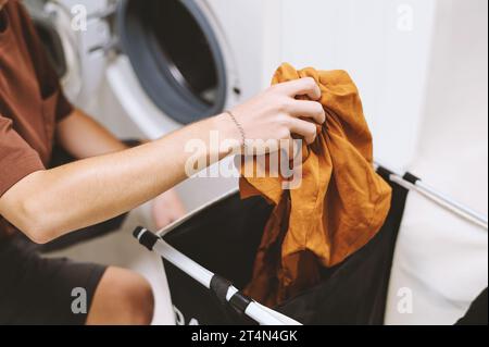Young man loading washing machine with dirty clothes Stock Photo