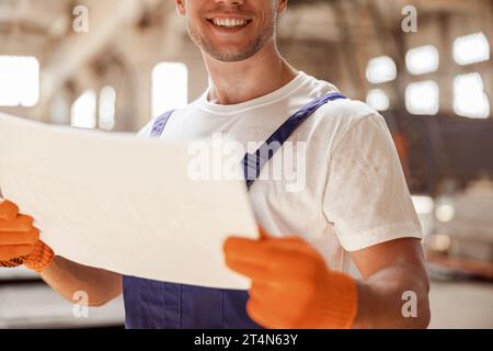 Joyful builder with architectural plan working at construction site Stock Photo