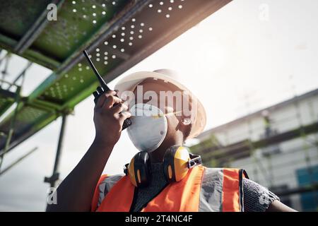 Its a beautiful day to build your dream. a young woman using a walkie talkie while working at a construction site. Stock Photo