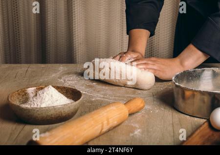 A woman kneads the dough with flour close-up. The cook prepares bread dough Stock Photo
