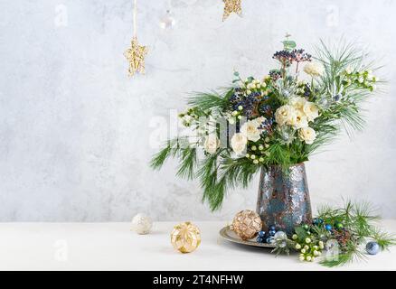 Christmas decorations, candles and flower bouquet. Winter arrangement with roses, fir branches, winter berries. Christmas flower still life. Stock Photo