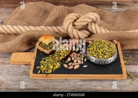 Chopped cut pistachio nuts Concept. Pistachios prepared for presentation in a copper bowl and on black marble. Ground, Milled, Crushed or Granulated P Stock Photo