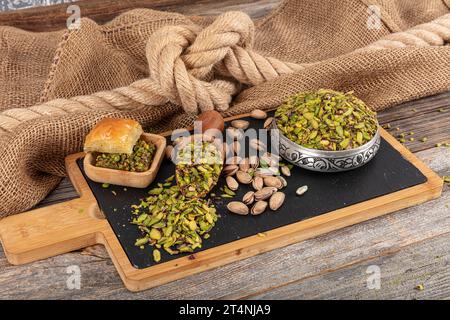 Chopped cut pistachio nuts Concept. Pistachios prepared for presentation in a copper bowl and on black marble. Ground, Milled, Crushed or Granulated P Stock Photo