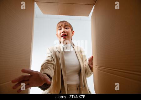 Taking out. Smiling young girl opening the box and stretching her hand Stock Photo