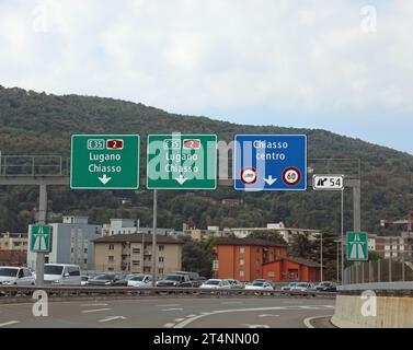 road signs for the cities of CHIASSO and Lugano near the border between Switzerland and Northern Italy Stock Photo