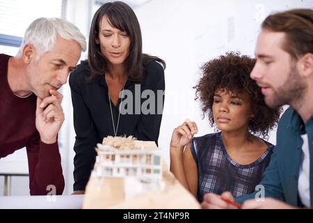 Contemplating his teams design. a group of architects working together on building plans. Stock Photo