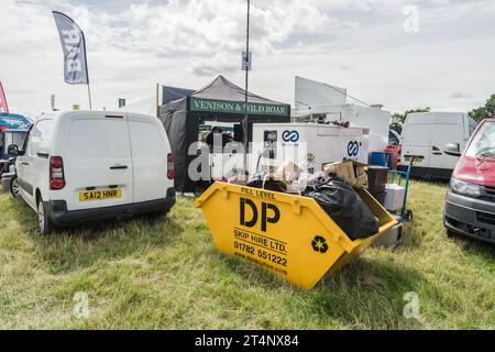 Nantwich, Cheshire, England, July 26th 2023. Yellow skip loaded with cardboard packaging and plastic black bin bags, waste editorial illustration. Stock Photo