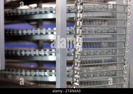 Spiral cooler for bread cooling in large bakery. Industrial spiral cooling tower conveyor machine. Selective focus. Stock Photo