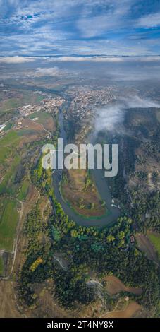 Vertical panoramic and aerial view of the meander of the Ter River as it passes through Roda de Ter on a foggy morning (Osona, Barcelona, Spain) Stock Photo