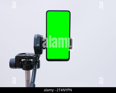 smartphone with green screen on tripod holder. smartphone mock up with chroma key Stock Photo