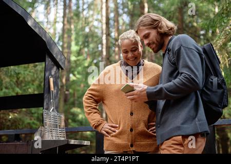 Young couple using smartphone together during their hiking in the forest Stock Photo