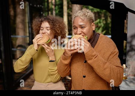 Young women eating homemade burgers at barbecue party Stock Photo - Alamy