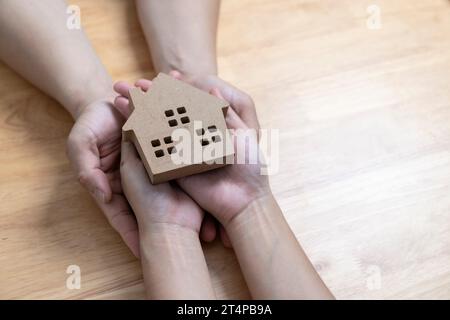hands holding wooden house, family home, homeless housing crisis, economic depression, mortgage concept Stock Photo
