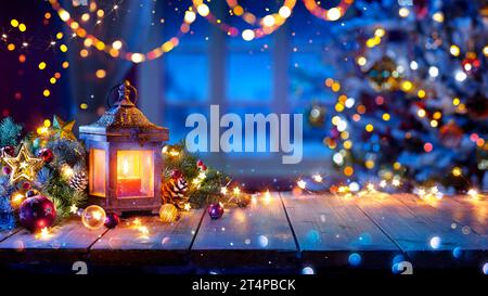 Lantern And Christmas Tree Glowing On Table With Decoration And String Lights - Bokeh And Glittering Effect On Background Stock Photo