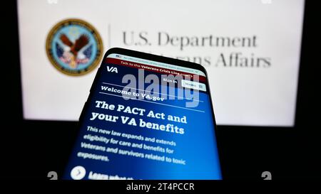 Smartphone with website of United States Department of Veterans Affairs (VA) in front of seal. Focus on top-left of phone display. Stock Photo