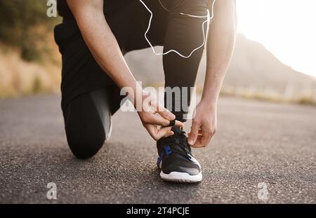 Lacing up to run in the direction of his goals. Closeup shot of an unrecognizable man tying his shoelaces while exercising outdoors. Stock Photo