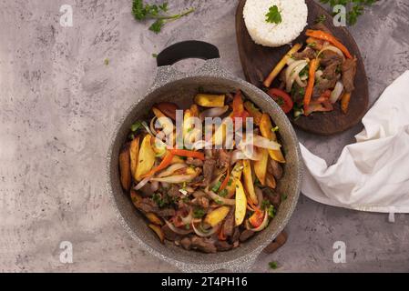 Dish named Lomo saltado, seen from above in a casserole and a wooden plate. Stock Photo