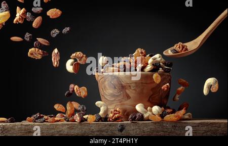 The mix of dried nuts and raisins in a wooden bowl on a black background. Copy space. Stock Photo