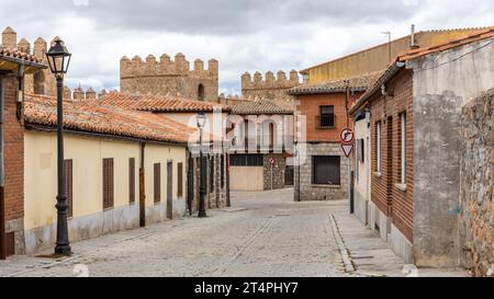 Narrow cobbled street in Avila, Spain, with old medieval buildings, old style street lamps and Wall of Avila, no people. Stock Photo