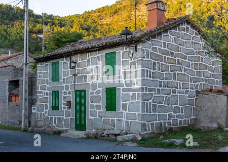 Old residential rural brick house with green doors and window shutters and tiled roof in a village in the province of Avila, Spain. Stock Photo