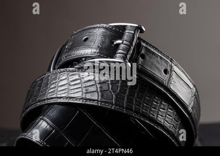 Part of a black crocodile leather belt. Expensive leather goods. Stock Photo
