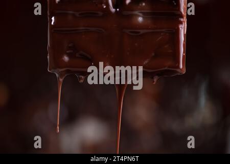 Melted chocolate drips down on a brown background. Stock Photo