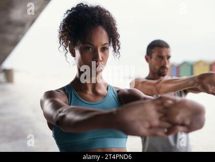 Were getting in shape together. a sporty young woman exercising with her boyfriend outdoors. Stock Photo