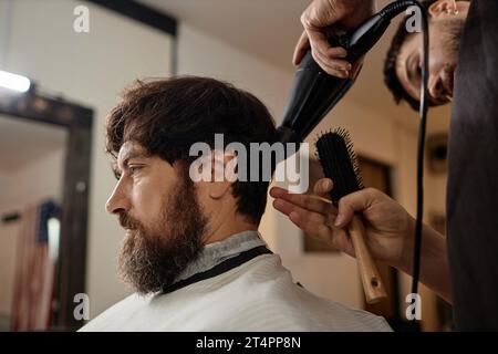 Bearded young man making a new haircut in barber shop Stock Photo