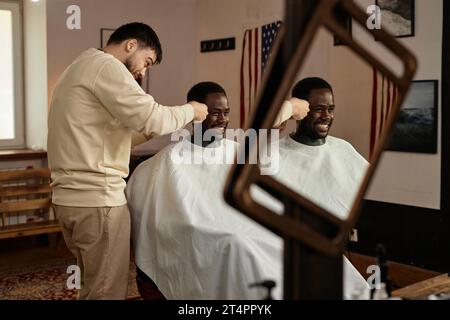 African American young man cutting his hair in barber shop Stock Photo