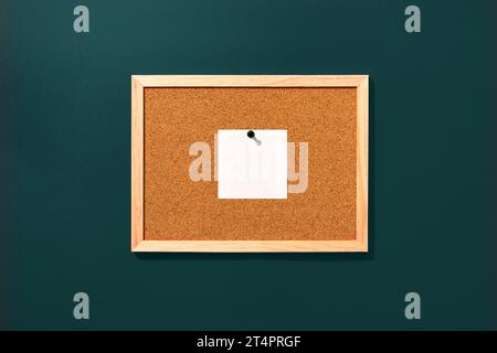 Cork board with wooden frame with one pinned blank note on blue background, top view with copyspace. Stock Photo