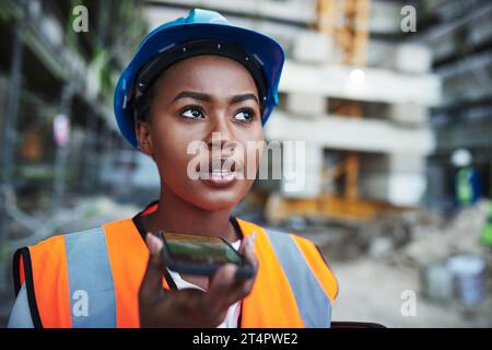 Leveraging new technology for large scale construction. a young woman using a smartphone while working at a construction site. Stock Photo