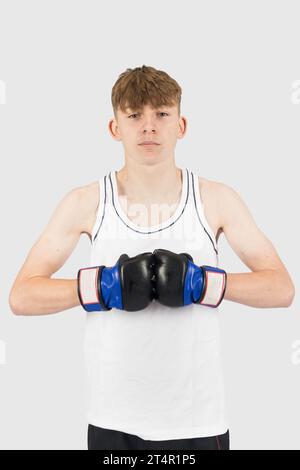 A caucasian teenage boy wearing MMA style boxing gloves celebrating ...