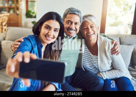 Capturing every special moment. a cheerful senior couple and their daughter taking a selfie together while sitting on a couch at home. Stock Photo