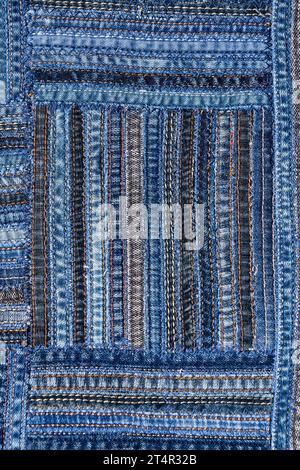 Close up view of denim fabric pattern in patchwork style, made of seams of old jeans. Stock Photo