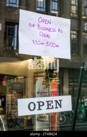 Open for business as usual sign on a shop window Stock Photo