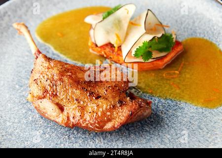 Duck confit served with carrot, black radish and orange sauce. Tasty and healthy dinner. Stock Photo