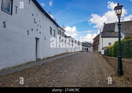Landscape a cobbled street in white Dutch town of Thorn against blue sky and clouds, post lamp, houses with white walls, gable tiled roofs, sunny day Stock Photo