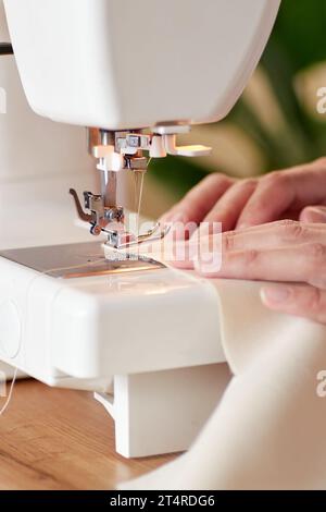 Hands of tailor woman stitching fabric using sewing machine. Stock Photo