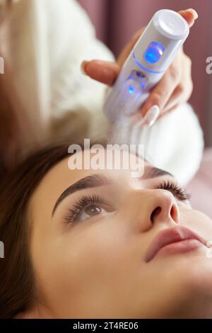 cosmetologist using primer spray for eyelash extension procedure in salon Stock Photo