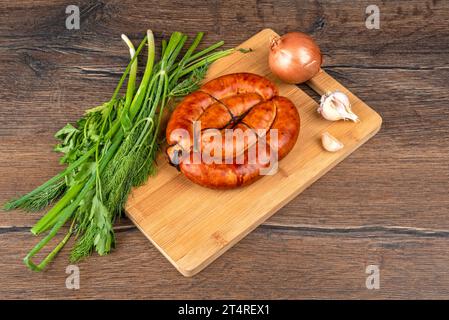 Fried homemade sausages on a wooden cutting board, garlic, onions and herbs. Copy space. Stock Photo